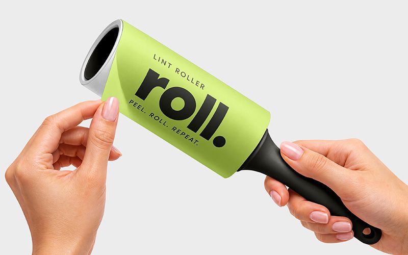 Lint roller mockup showing hands lifting a lime green protective wrapper with bold black lettering