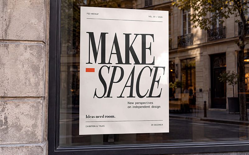 Shop window poster mockup with black MAKE SPACE lettering on cream paper and reflected buildings in the glass