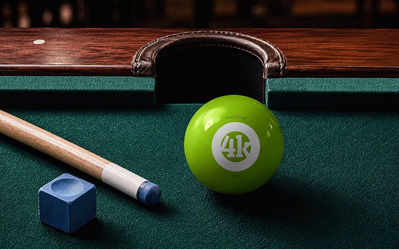 Free billiard ball mockup PSD with glossy green pool ball, wooden cue, blue chalk, and dark green table cloth.