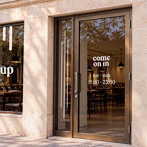Restaurant window mockup with cream logo lettering on a glass storefront