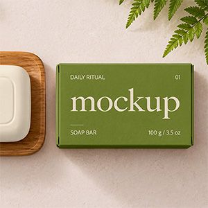 Ivory soap bar and olive green packaging box with cream lettering in a botanical spa scene